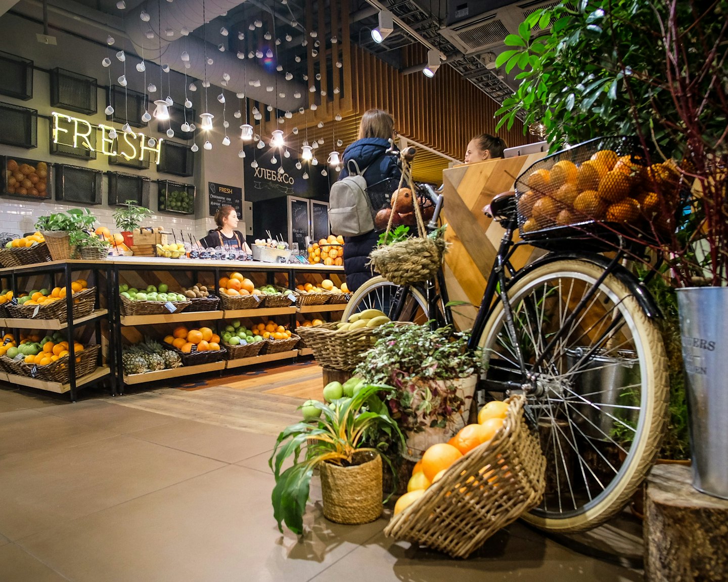 Kunden und Mitarbeiter interagieren in einem Lebensmittelgeschäft mit frischem Obst und Gemüse.