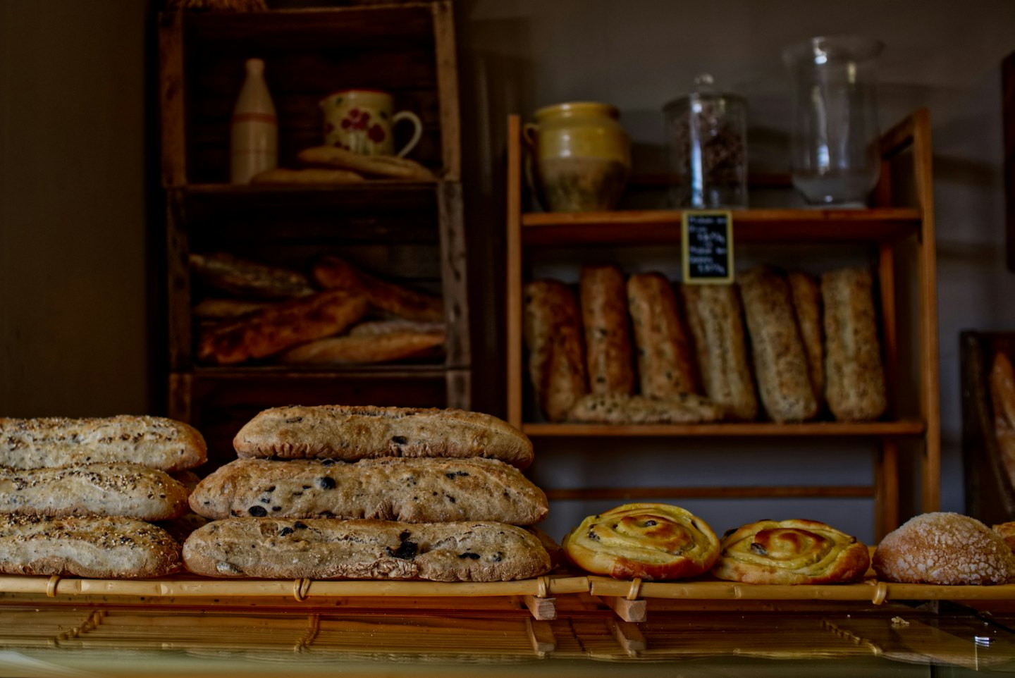 Frisch gebackenes Brot und goldene Gebäckstücke auf einer Holztheke.