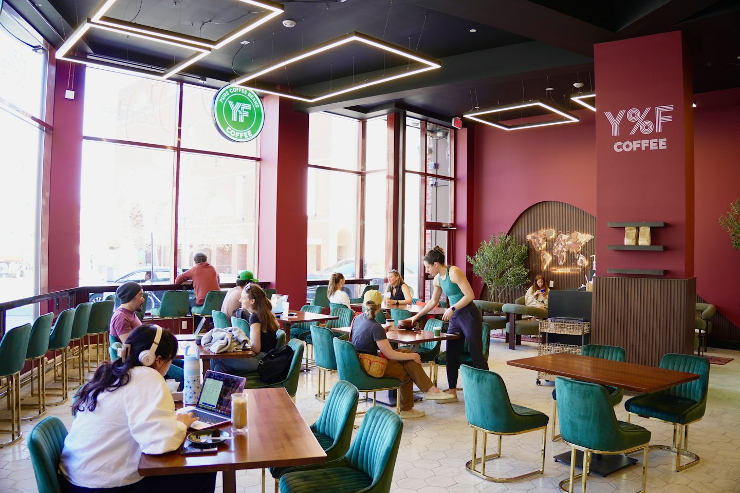 Kunden arbeiten und unterhalten sich an Holztischen in einem Café.